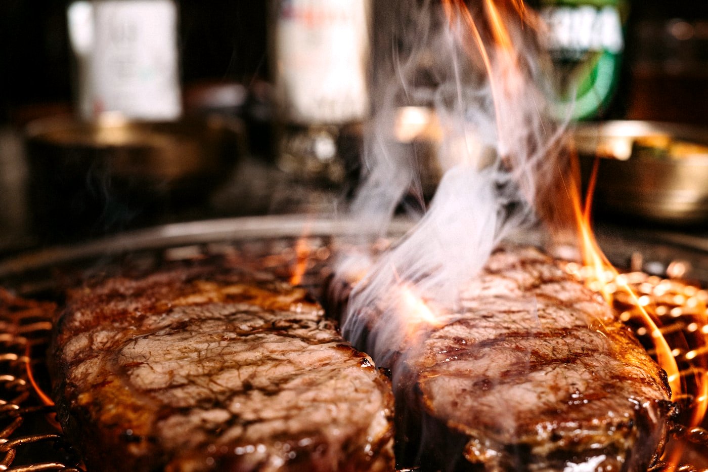 A charcoal Korean BBQ grill with marbled beef searing over glowing embers